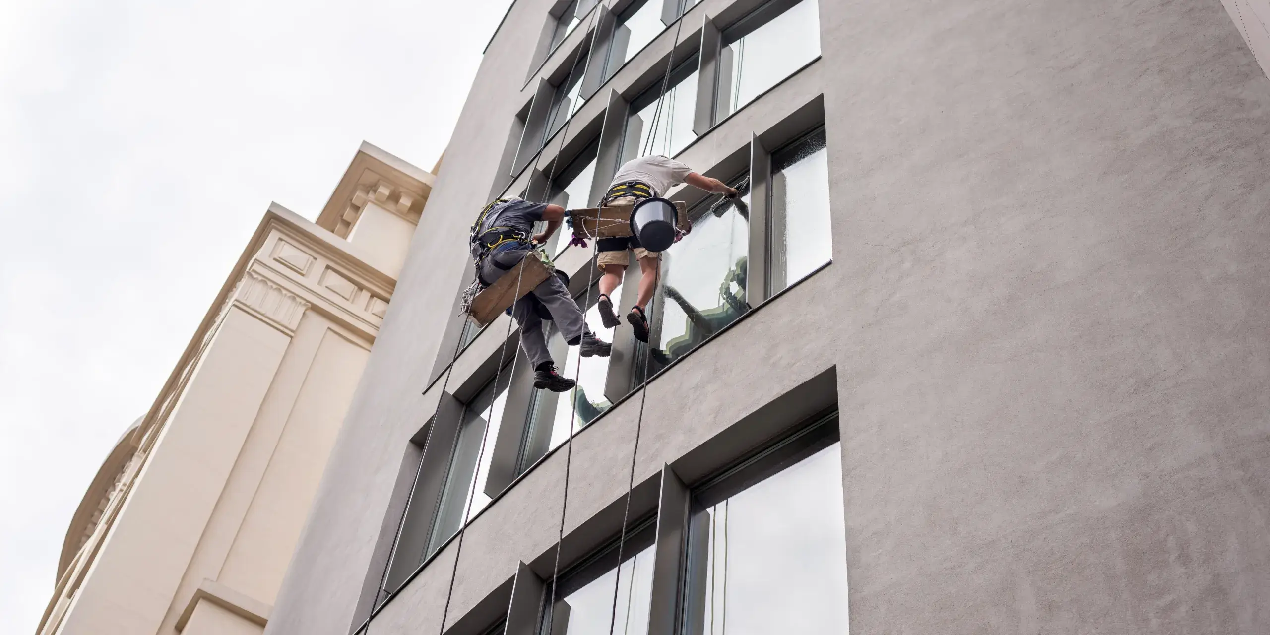 two-workers-washing-windows-outside-building